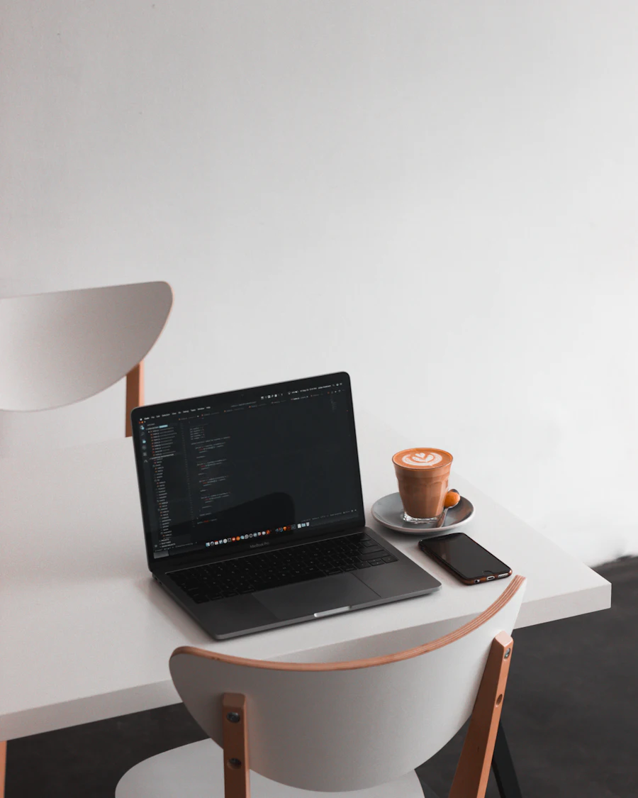 A laptop showing code beside a coffee on a white desk